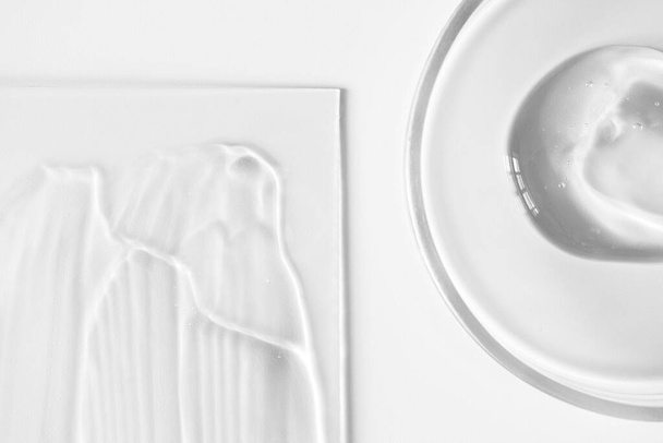 Közelkép aloe gél üveg Petri-csészében és átlátszó bőrápoló krém üveg fehér alapon, felett. Tiszta textúra hidratáló sampon vagy maszk - Fotó, kép