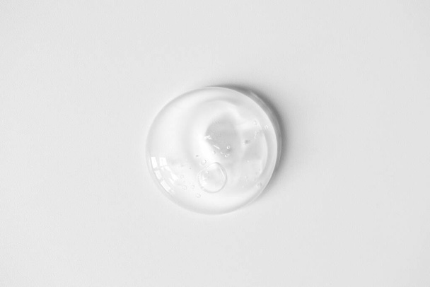 Mancha de gel de aloe con burbujas de aire sobre fondo blanco. Limpiador facial transparente puro, pelado, champú o gel de ducha, vista superior
 - Foto, Imagen