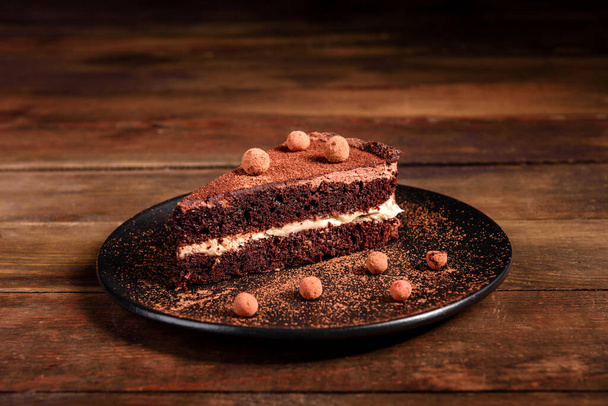 Um pedaço de delicioso bolo de chocolate com bagas, creme e chocolate em pó
 - Foto, Imagem