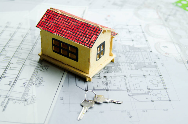 Modelo de la casa en el proyecto arquitectónico impresión azul con llaves de nuevo hogar. Inversión para casa vacante. Concepto de crédito bancario. - Foto, imagen