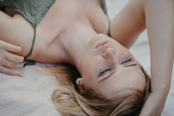 young attractive woman lies on a white plaid in a thin olive-colored top. Upside down portrai - 写真・画像