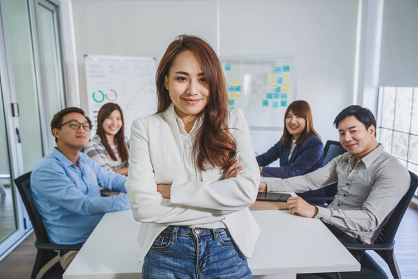 Portrait d'une femme d'affaires asiatique avec les bras croisés et debout sur le groupe de collègues partenaires lors d'une réunion de remue-méninges sur le lieu de travail moderne, concept des ressources humaines et propriétaire de petite entreprise
 - Photo, image