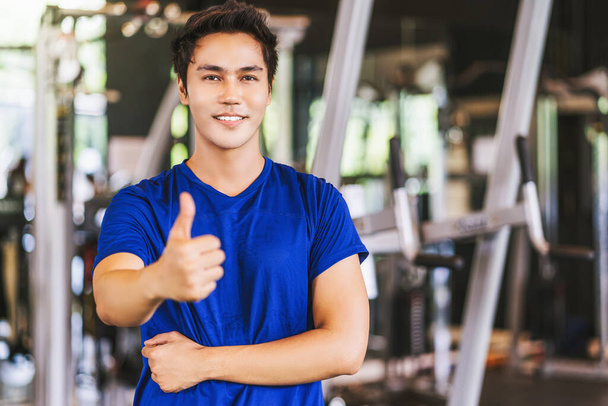 Portrait of Young Asian man wearing sportswear and Raising hands like in gym fitness sport complex, posture position, sport club community, sports and healthcare concept, - Photo, Image