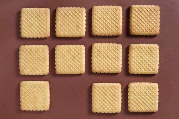Background of square cookies on brown surface, top view - Foto, Bild