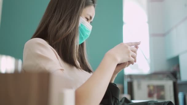 4K Asian woman wear mask using smart phone, female sit down holding cellphone reading online health articles, self prevention from disease, social issues, health issues, life insurance commercial - Footage, Video