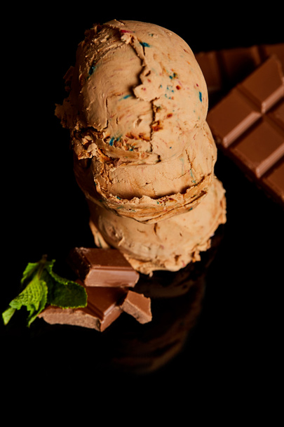 ミントの葉が黒で隔離された新鮮なおいしいチョコレートアイスクリーム - 写真・画像