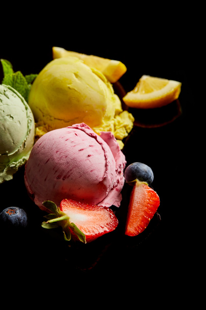 selective focus of delicious lemon, berry and mint ice cream balls isolated on black - Foto, immagini