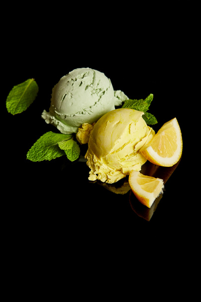 fresh delicious lemon and mint ice cream isolated on black - 写真・画像