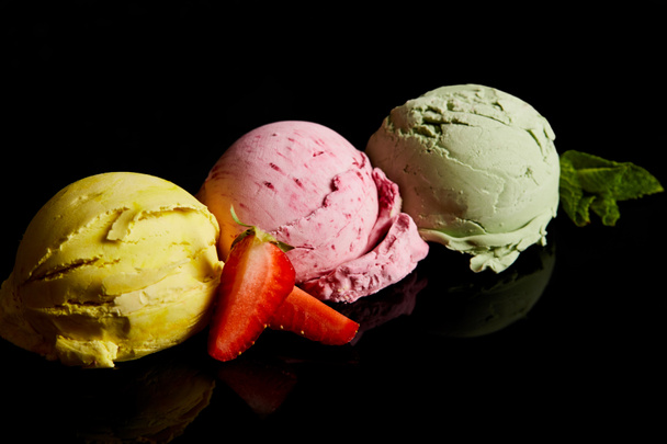 delicious lemon, strawberry and mint ice cream balls isolated on black - Foto, Imagen