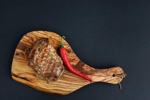 Fresh meat steak and seasonings on rustic wooden board over black background. Top view, flat lay, copy space banner. - Photo, Image