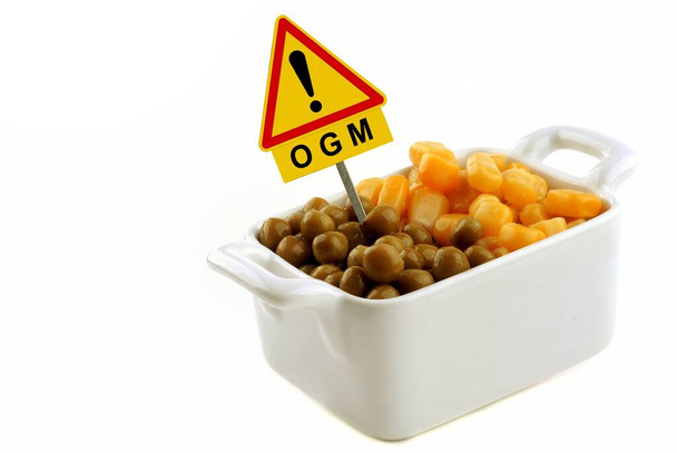 Concept of genetically modified organism with corn and peas in a ramekin with a road sign - Photo, Image