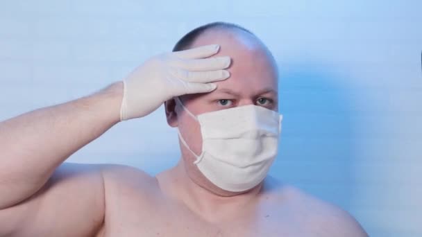 Een man met een medisch masker speelt op de camera. - Video