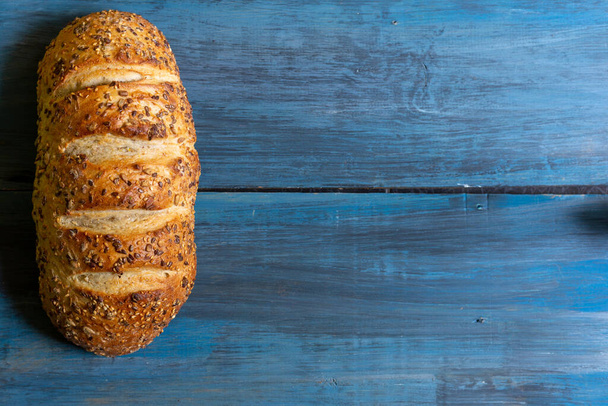 Pan de semilla artesanal sobre una mesa azul, ideal para tapas o sándwiches
 - Foto, imagen