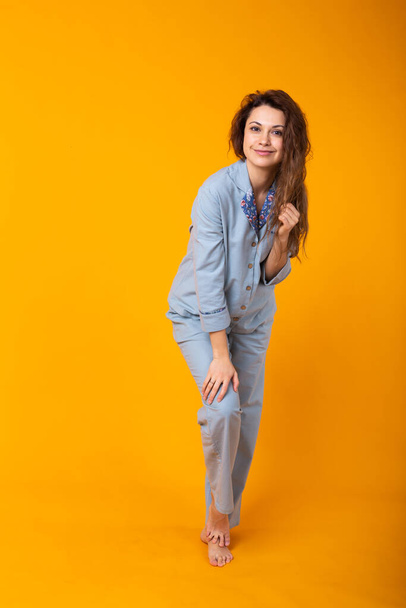 Nahaufnahme einer jungen Frau in blauer Hauskleidung. Vereinzelt auf gelbem Hintergrund. Pyjama-Konzept. - Foto, Bild