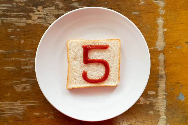 El pan del desayuno es escrito 5 por el ketchup en el plato de la escritura. A a Z y Conjunto de caracteres especiales y número
. - Foto, Imagen