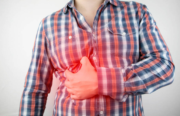Een man grijpt zijn rechterkant onder de ribben. Pijn in de lever. Pijnsyndroom bij leverziekte. - Foto, afbeelding