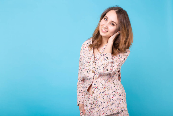 Smiling young girl in pajamas home wear posing while resting at home isolated on blue background studio portrait. Relax good mood lifestyle concept. - Photo, Image