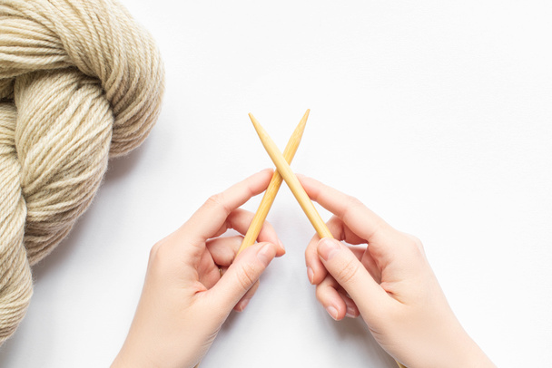 top view of female hands with beige yarn and knitting needles on white background - Photo, Image