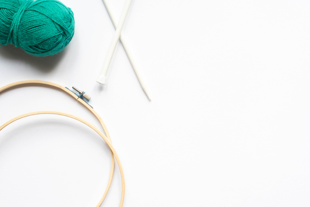 白い背景に緑の毛糸と編み物の織機と編物の針のトップビュー - 写真・画像