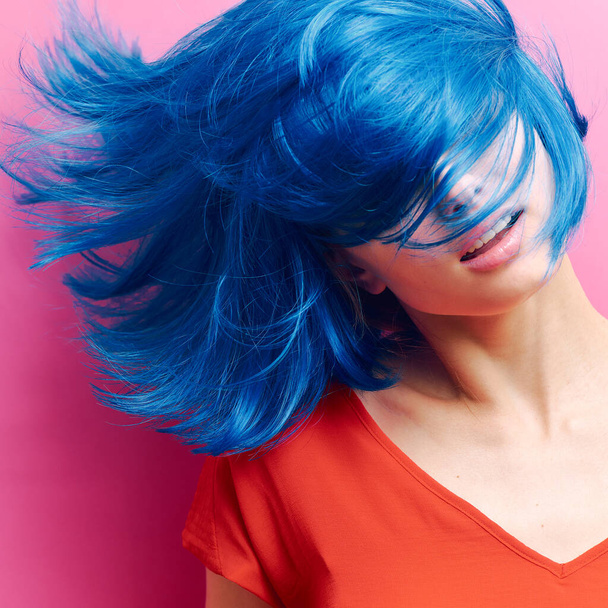 studio portrait of a sexy beautiful girl with a smile in motion on a pink background. Girl with blue hair - Fotó, kép