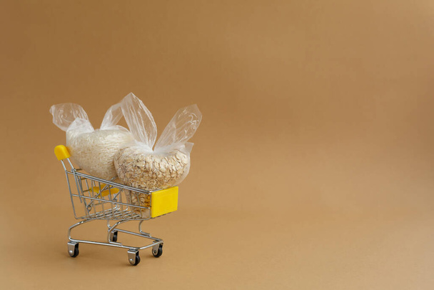 various groats in packages in a grocery cart on a brown background. Rice and oatmeal - Photo, Image