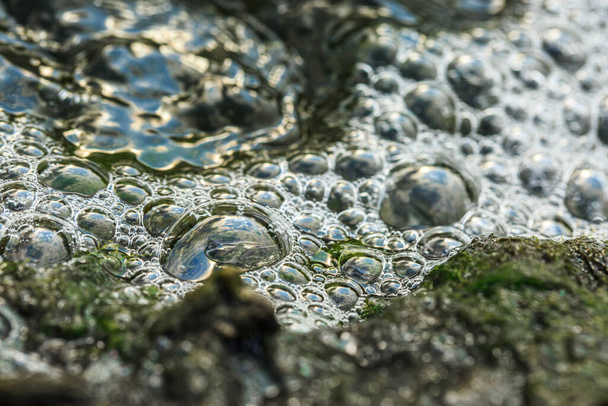 Kuplia vedessä lähellä kiveä
 - Valokuva, kuva