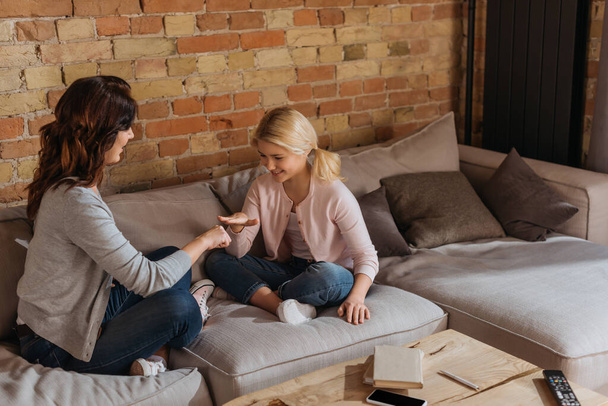 Criança sorridente jogando tesoura de papel de rocha com a mãe na sala de estar
 - Foto, Imagem