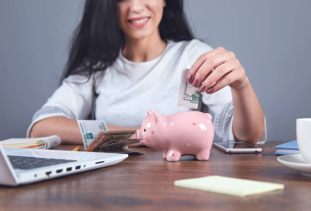 woman hand money with piggy bank on working desk - Foto, afbeelding