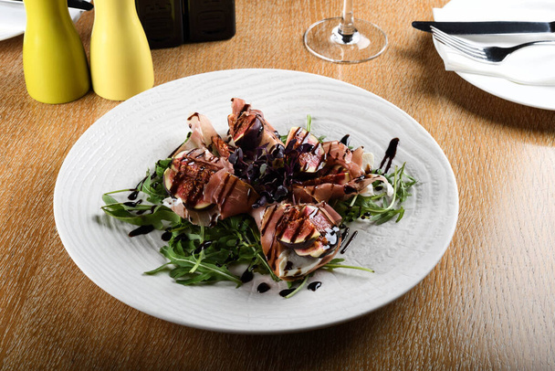 Traditional Italian salad made with figs, Prosciutto dry-cured ham or Parma ham thinly sliced prosciutto crudo served on a white plate in an Italian Restaurant - Foto, Imagem