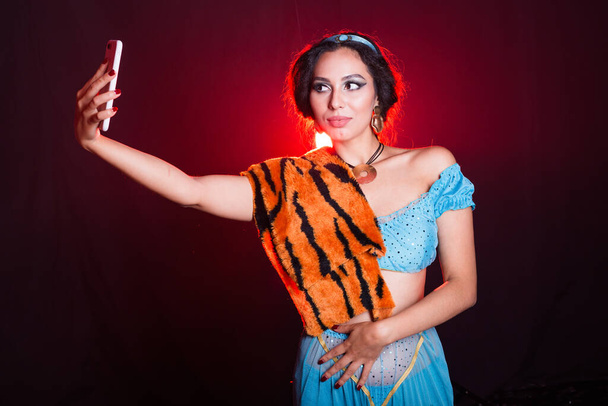 Girl doing selfie with tiger skin, crazy photos. Dont eco friendly lifestyle. Young woman takes pictures of herself in the phone. Life in social networks, narcissism, modern personality. Personality - Photo, Image