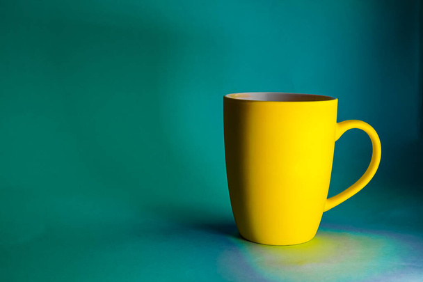 Yellow mug against a blue background in natural light - contrasting photo with space for writing text - Photo, Image