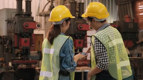 Két fiatal mérnök beszélget és nézi a mobiltelefont a gyárfejlesztésről.. - Felvétel, videó