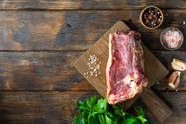 Carne crua de vaca em uma tábua de madeira em uma mesa de cozinha de madeira marrom. Um pedaço de carne fresca. Vista superior com espaço para texto
 - Foto, Imagem
