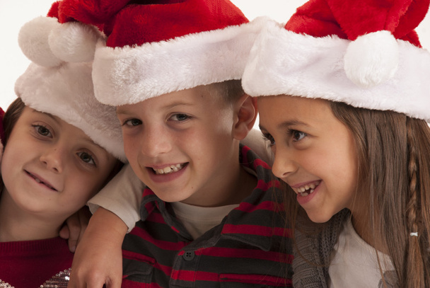 Three children in santa hats smiling - Foto, Imagen