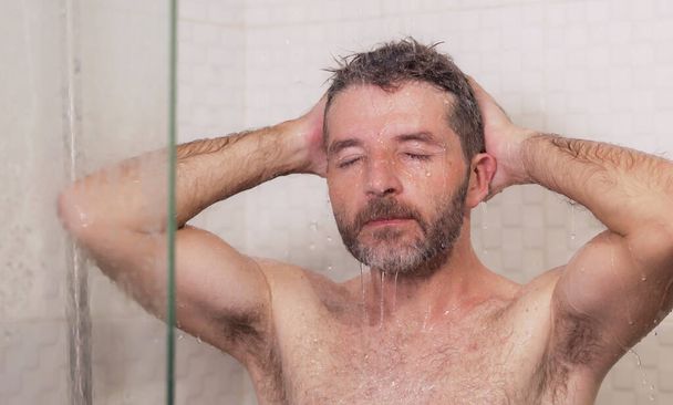 young attractive and happy man with beard taking a shower at home washing his hair with shampoo cheerful enjoying the morning shower in wellness and hygiene concept - Fotoğraf, Görsel