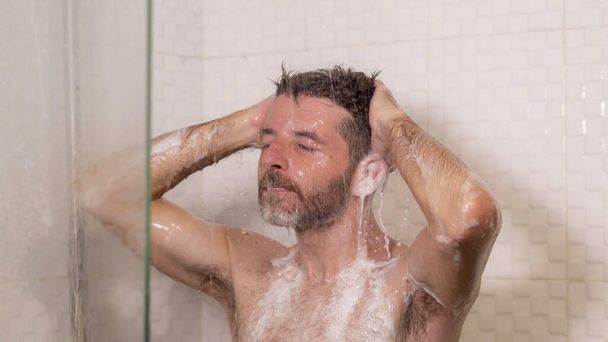 morning shower - lifestyle portrait of young attractive and happy man with beard taking a shower at home washing his hair with shampoo enjoying cheerful in wellness and hygiene concept - Φωτογραφία, εικόνα