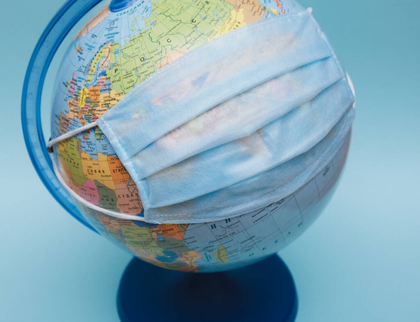 Medizinische Schutzmaske auf einem Globus in Großaufnahme - Foto, Bild