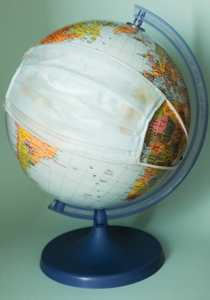 Medizinische Schutzmaske auf einem Globus in Großaufnahme - Foto, Bild