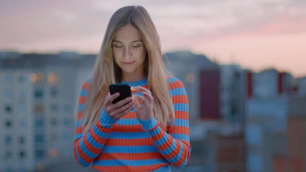 Fiatal Y-generációs nő használja okostelefon naplementekor - Felvétel, videó