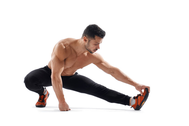 Shirtless bodybuilder stretching on floor. - Valokuva, kuva