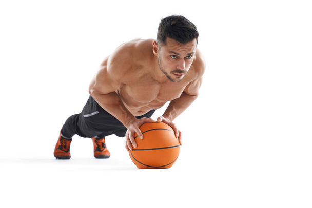 Shirtless bodubuilder doing push ups using basketball. - Foto, afbeelding