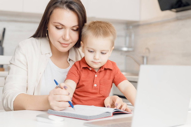 Beautiful woman helps son learn how to write alphabet letters. Online learning concept - Foto, Imagem
