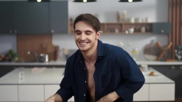 Attractive man dancing at home kitchen. Sexy man in open skirt posing to camera - Imágenes, Vídeo