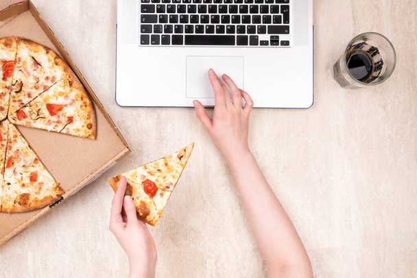 Pizza in a cardboard box and laptop on a light marble background. Copy space for your text. Top view, flat lay. Takeaway food concept - Fotó, kép