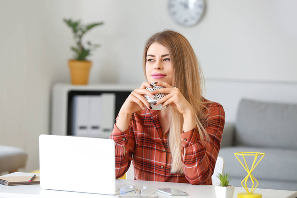 Красивая молодая женщина с чашкой кофе сидя за столом
 - Фото, изображение