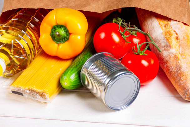 Закрыть различные здоровую пищу, помидоры, хлеб, макароны в бумажном пакете на белом фоне. Концепция доставки продуктов питания
 - Фото, изображение