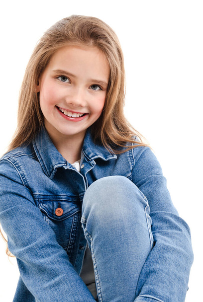 Portrait of adorable smiling little girl child preteen sitting isolated on a white background - Photo, image