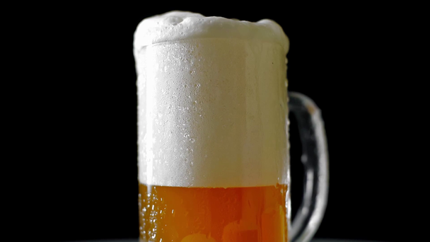 кружка, полная холодного светлого пива с пеной, вращающиеся изолированы на черном
 - Кадры, видео