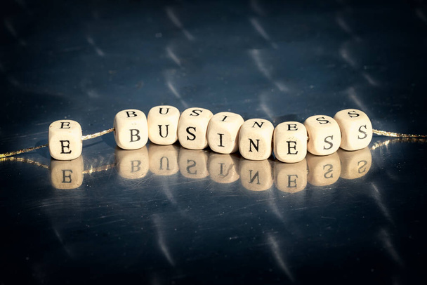 Wooden cubes with e business inscription strung on a thread on reflective table. The online business concept. - Photo, image