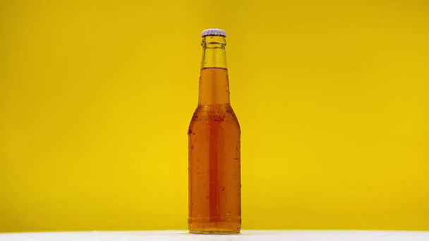 bottle of light beer rotating on white surface isolated on yellow - Footage, Video